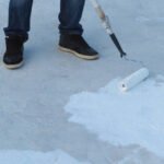 Man applies waterproof and thermal insulation of a roof from rain and sun.